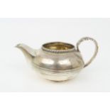 A GEORGE III SILVER CREAM JUG of teapot form, with central banding, a gadrooned rim and acanthus