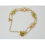 AN ARTS & CRAFTS BRACELET mounted in 15ct gold and set with hexagonal cut peridots, and mabe pearls.