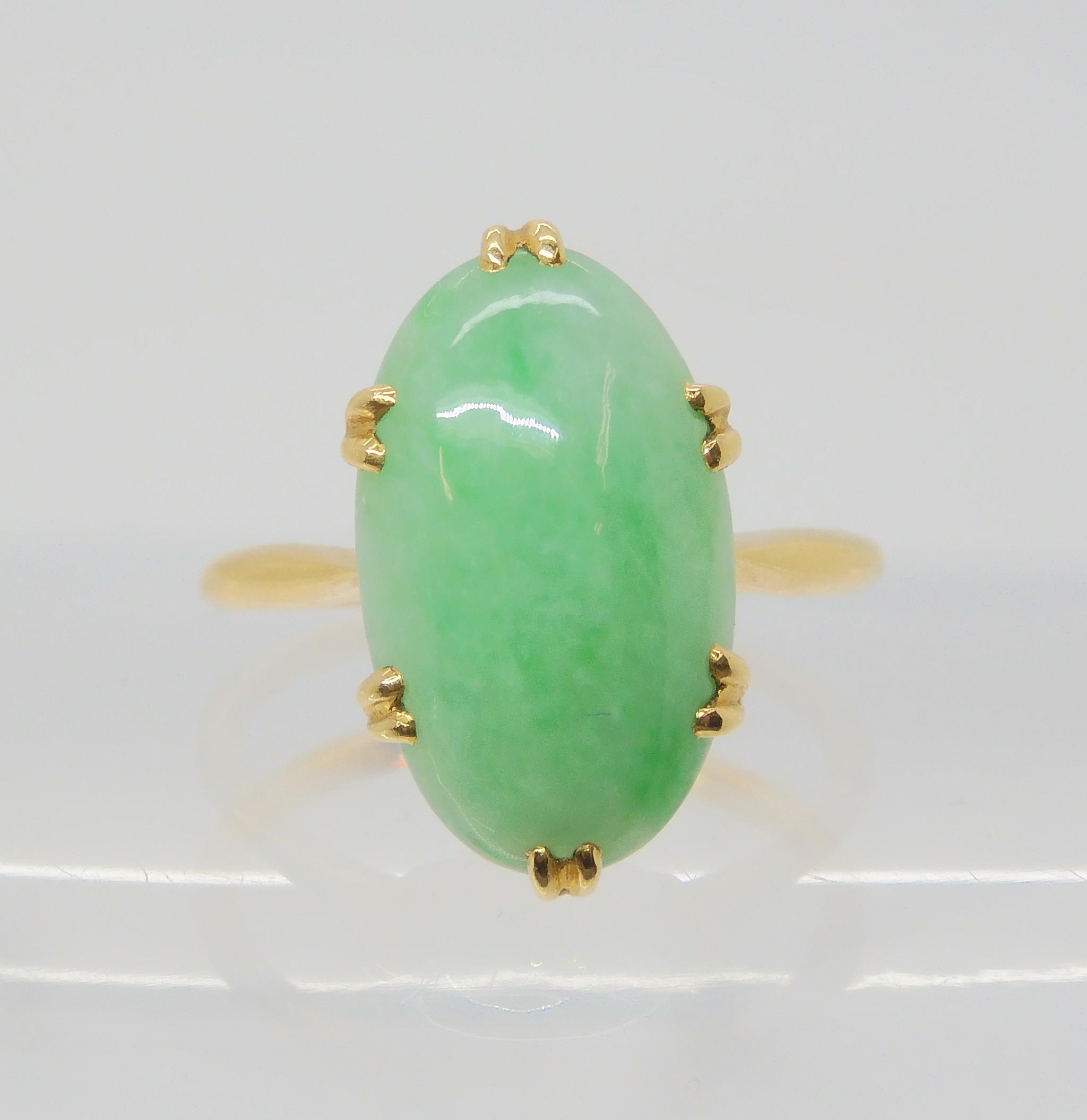 A CHINESE GREEN HARDSTONE RING mounted in bright yellow metal, the hardstone measures approx 16mm