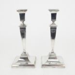 A PAIR OF EDWARDIAN SILVER CANDLESTICKS of tapering square form, on stepped sloping square bases,