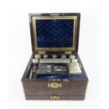 A VICTORIAN BRASS BOUND MAHOGANY TRAVELLING TOILETRY BOX comprising silver topped vanity jars and