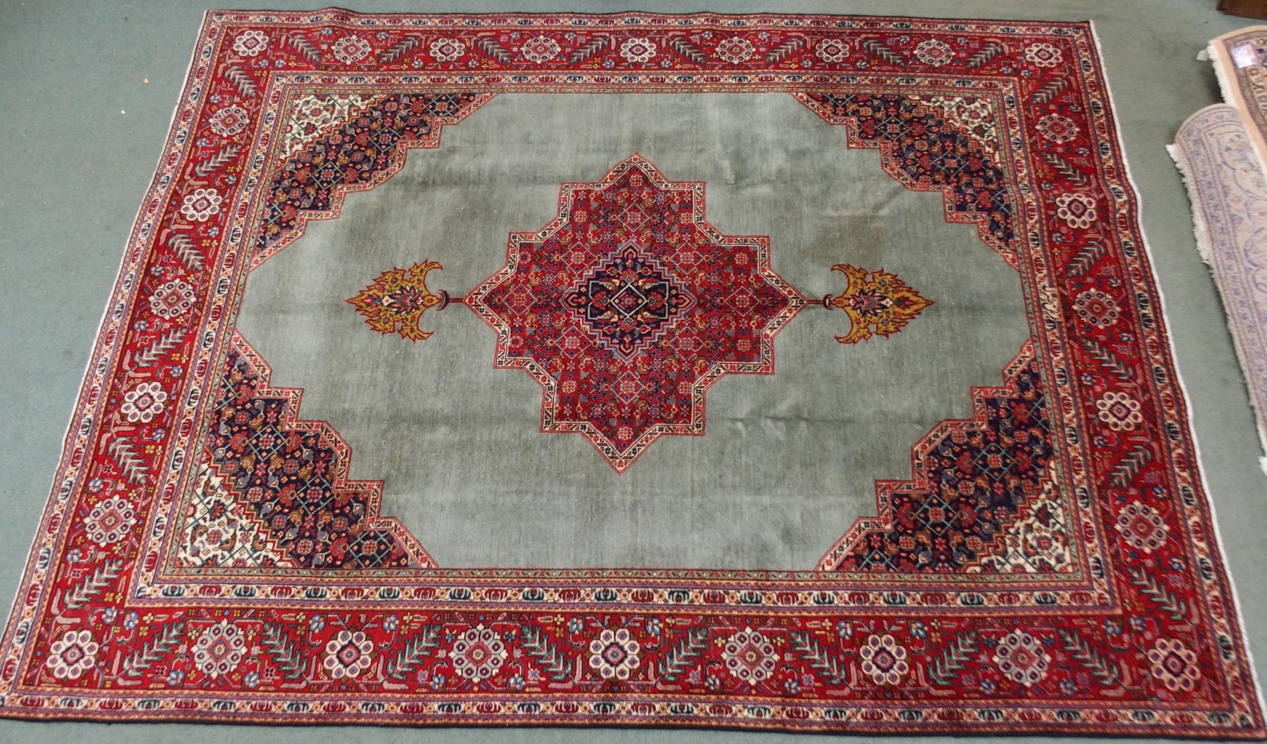 A GREEN GROUND TABRIZ RUG with red geometric central medallion, dark blue and white spandrels and