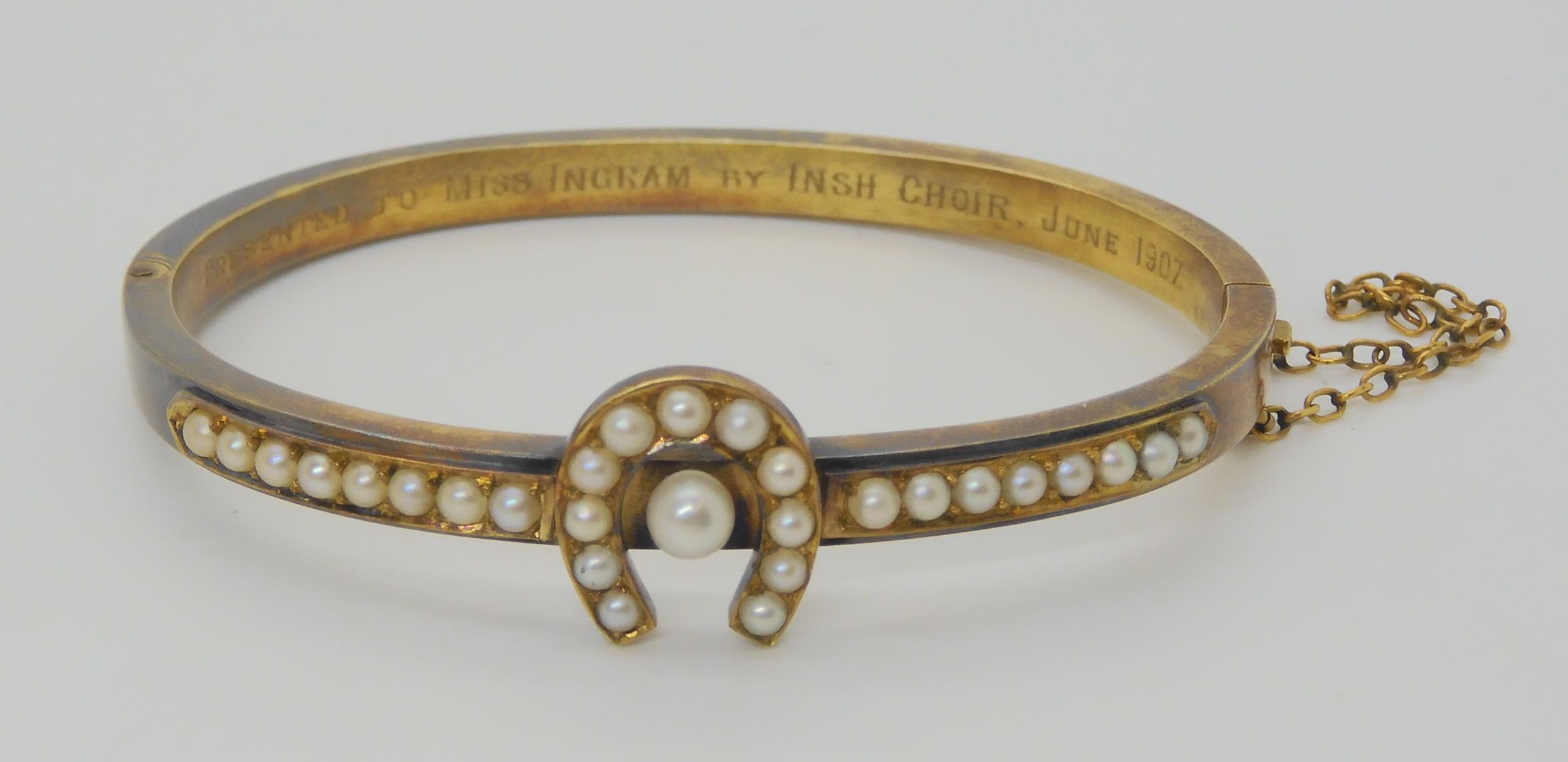 A PEARL SET HORSESHOE BANGLE mounted in yellow metal, with inscription to the inner shank dated