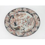 A LARGE IMARI CIRCULAR DISH  Painted with a garden table and objects amongst prunus, chrysanthemum
