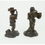 A PAIR OF JAPANESE BRONZE FIGURE CANDLESTICKS Cast as a man carrying reeds and a woman carrying a