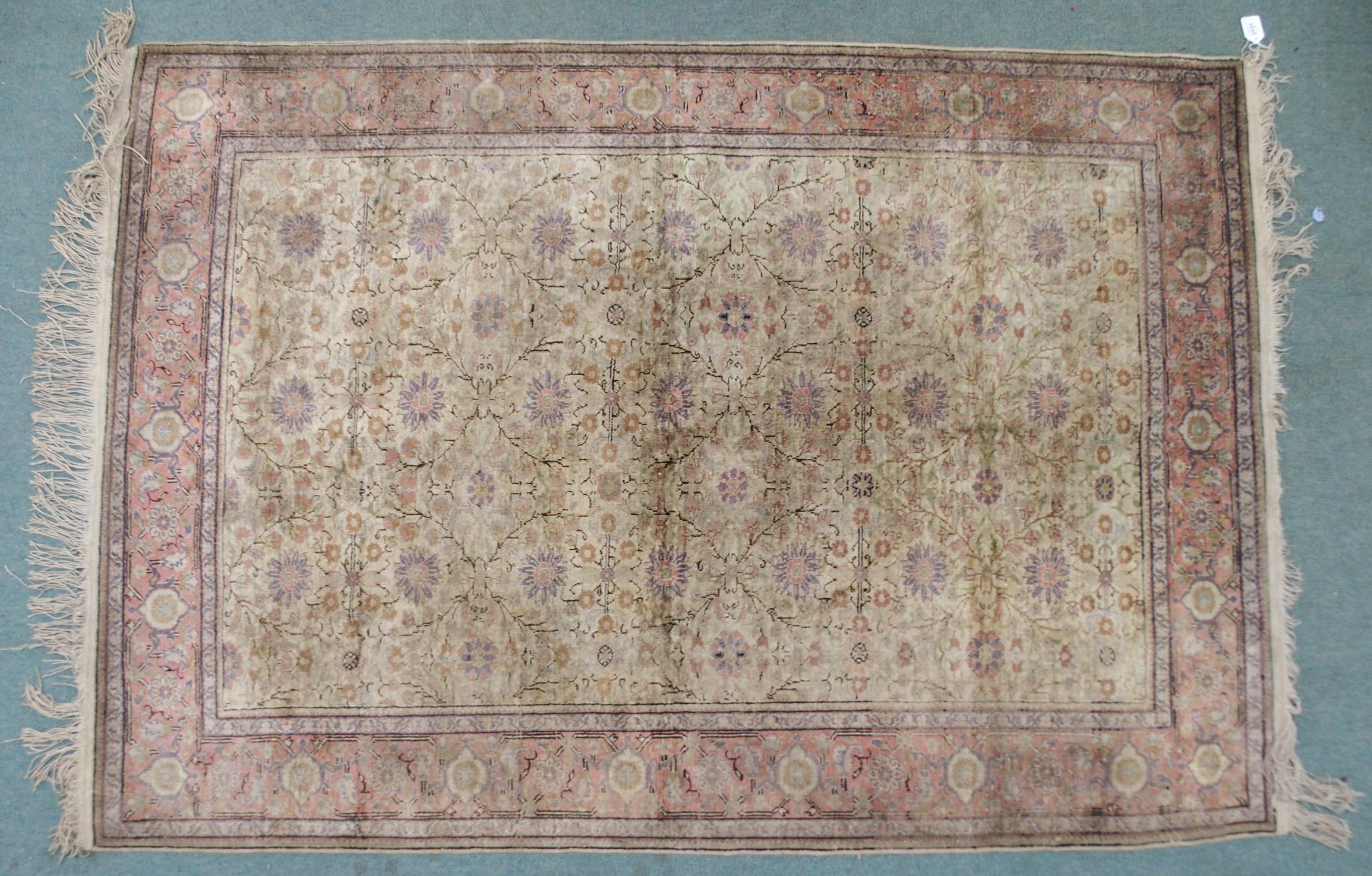 A CREAM GROUND SILK AND WOOL PERSIAN RUG with floral foliate all-over design and pink borders, 185cm