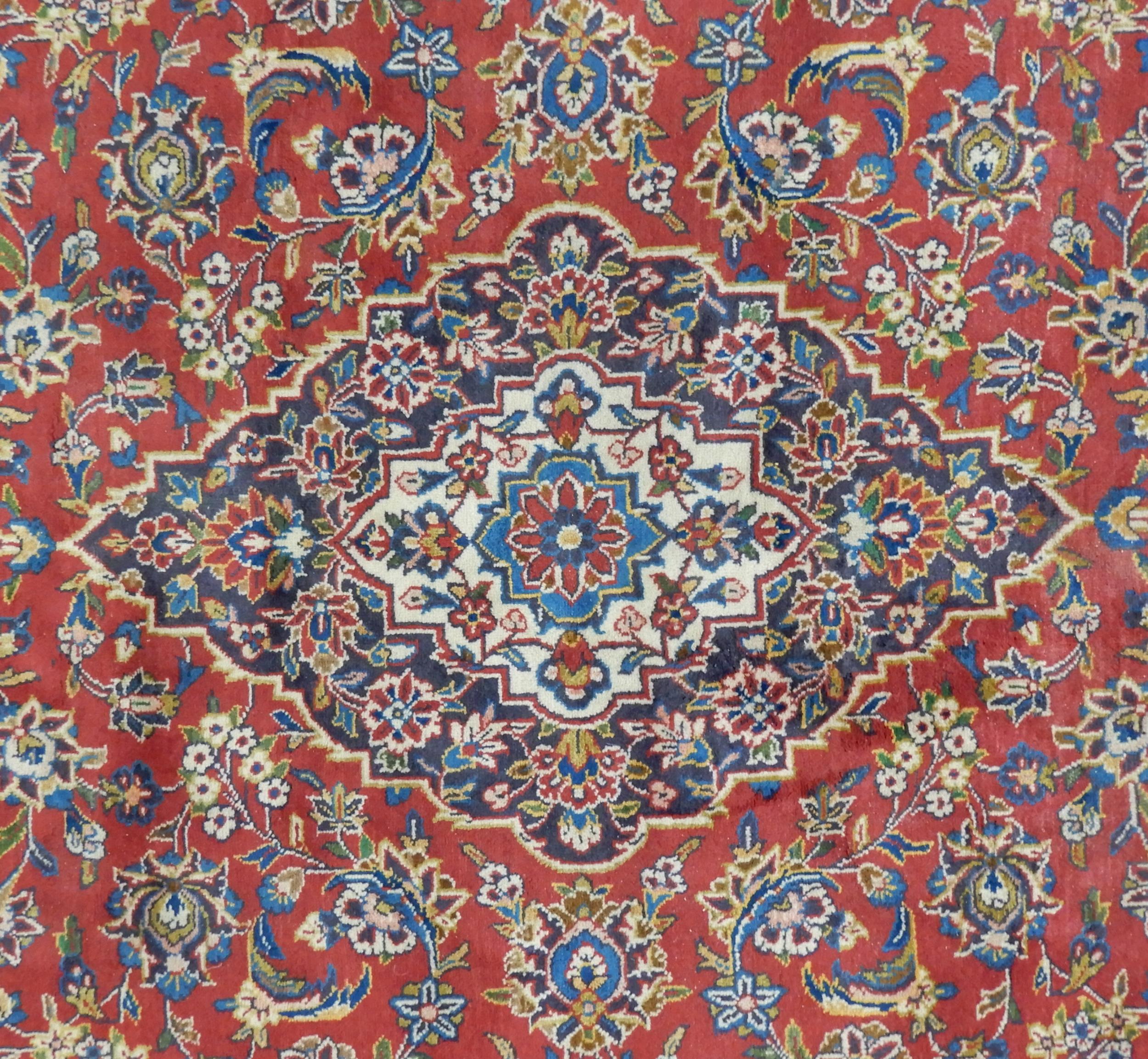 A RED GROUND KESHAN RUG with all over floral foliate design, dark blue central medallion, matching - Image 2 of 5