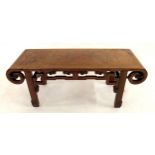 A 20TH CENTURY CHINESE HARDWOOD LOW TABLE with top terminating in scrolled ends over carved frieze