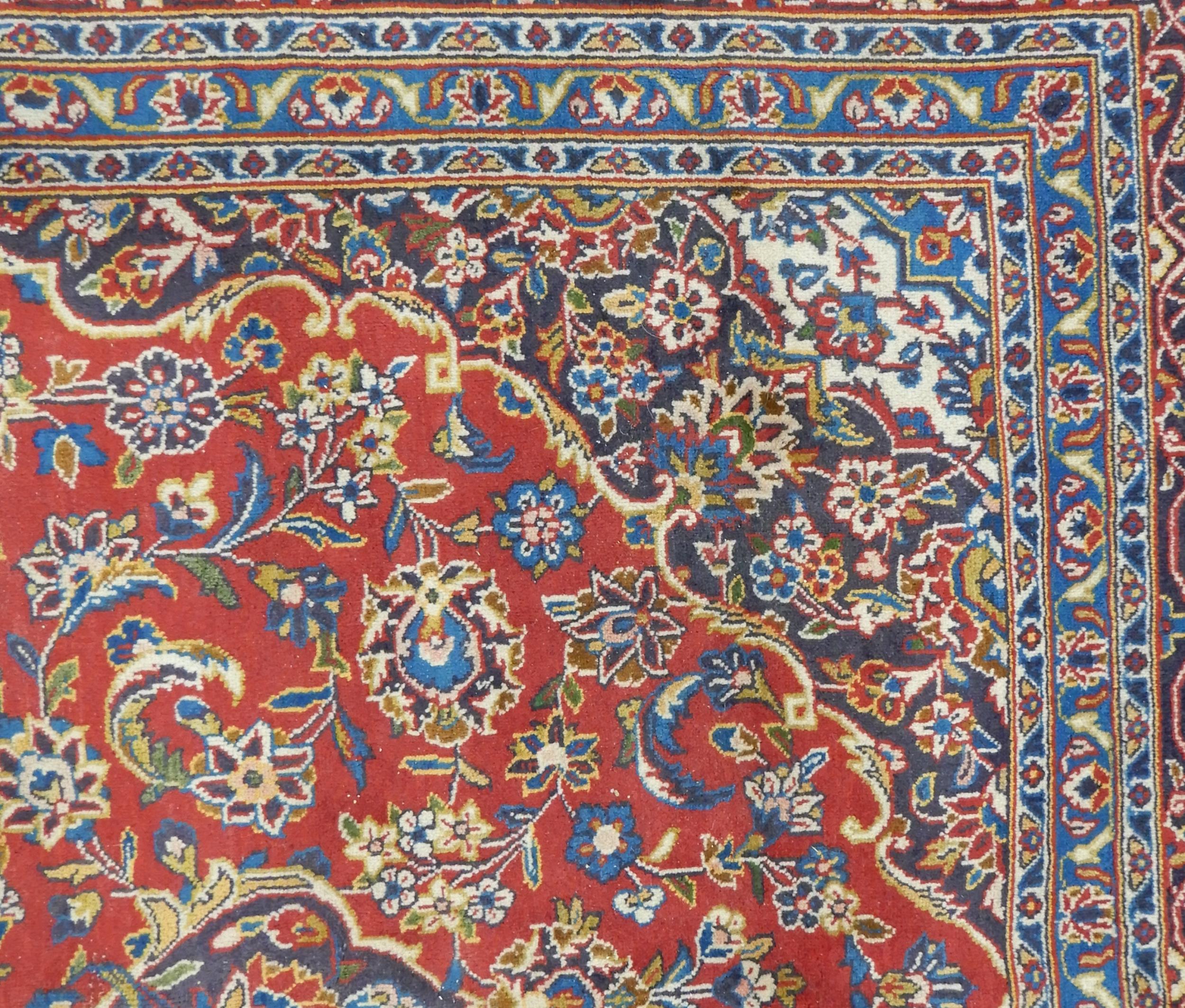 A RED GROUND KESHAN RUG with all over floral foliate design, dark blue central medallion, matching - Image 3 of 5