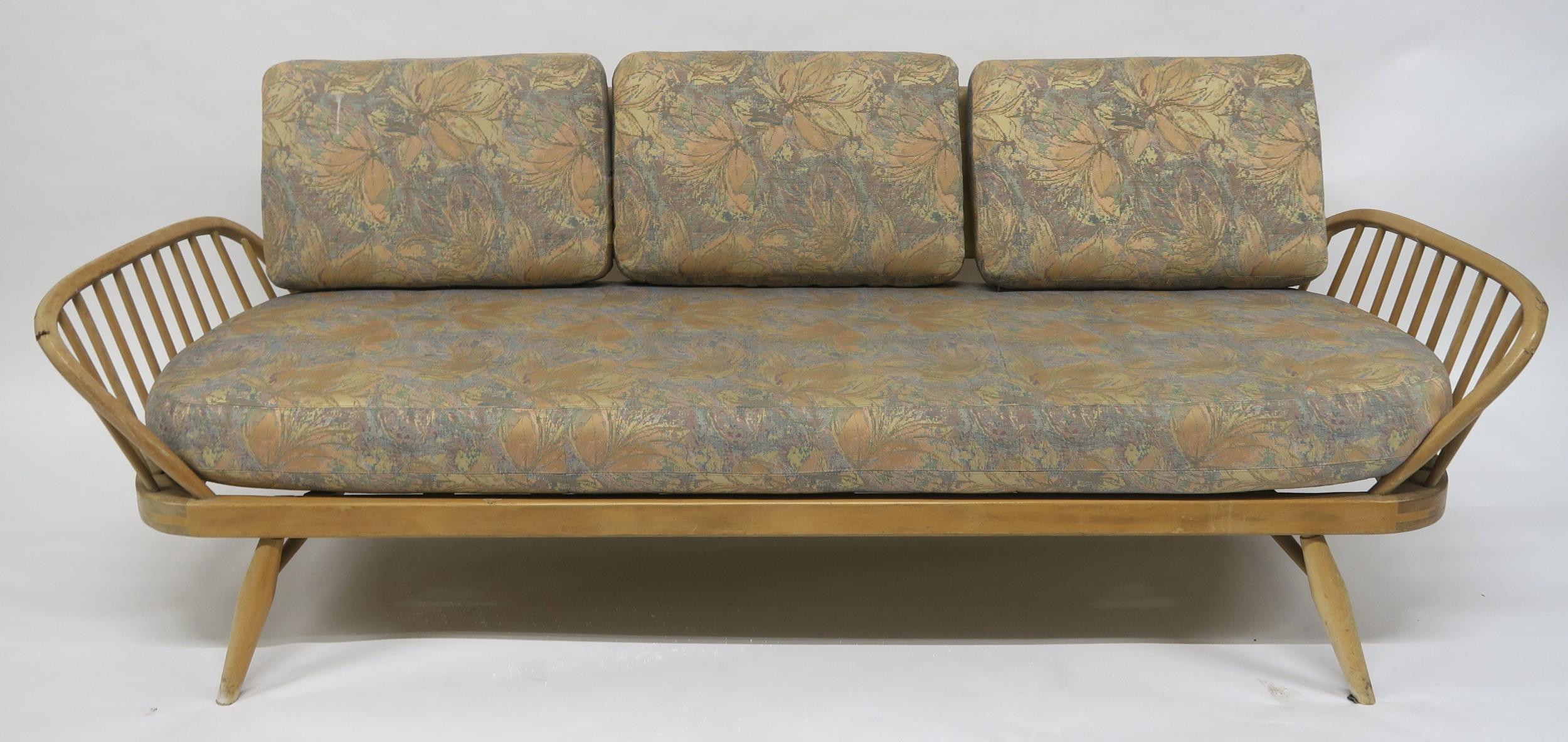 A MID 20TH CENTURY ELM AND BEECH FRAMED ERCOL DAY BED with floral upholstered cushions, 77cm high