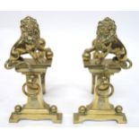 A PAIR OF EARLY 20TH CENTURY CAST BRASS FIRE DOGS mounted with figural lions, 46cm high x 23cm