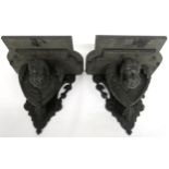 A PAIR OF 19TH CENTURY EBONISED WALL BRACKETS with shaped moulded tops over carved cherubs heads