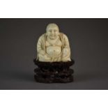 A Chinese carved ivory Buddha on carved hardwood base