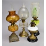 Four various cast metal and glass oil lamps