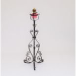 A wrought iron and cranberry glass oil lamp standard