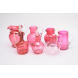 Fifteen assorted cranberry glass jugs and decanters, predominantly Victorian, including dimple and