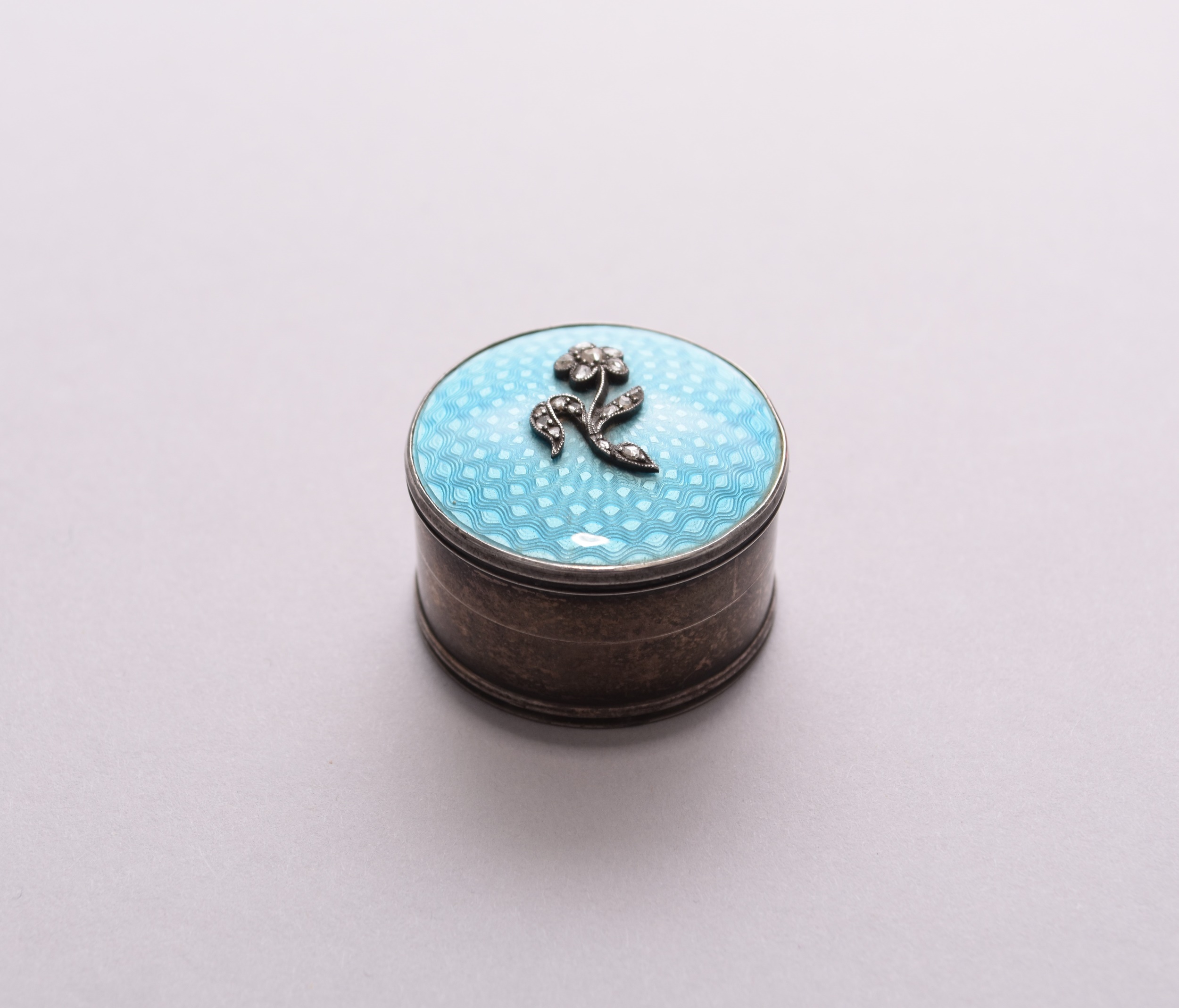 A silver and enamel diamond set pill box