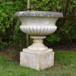A late 19th century composition stone urn, on a marble socle and plinth
