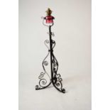 A wrought iron and cranberry glass oil lamp standard