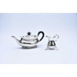 A silver teapot and cream jug