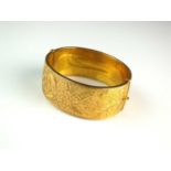 A 9ct gold bright cut engraved bangle