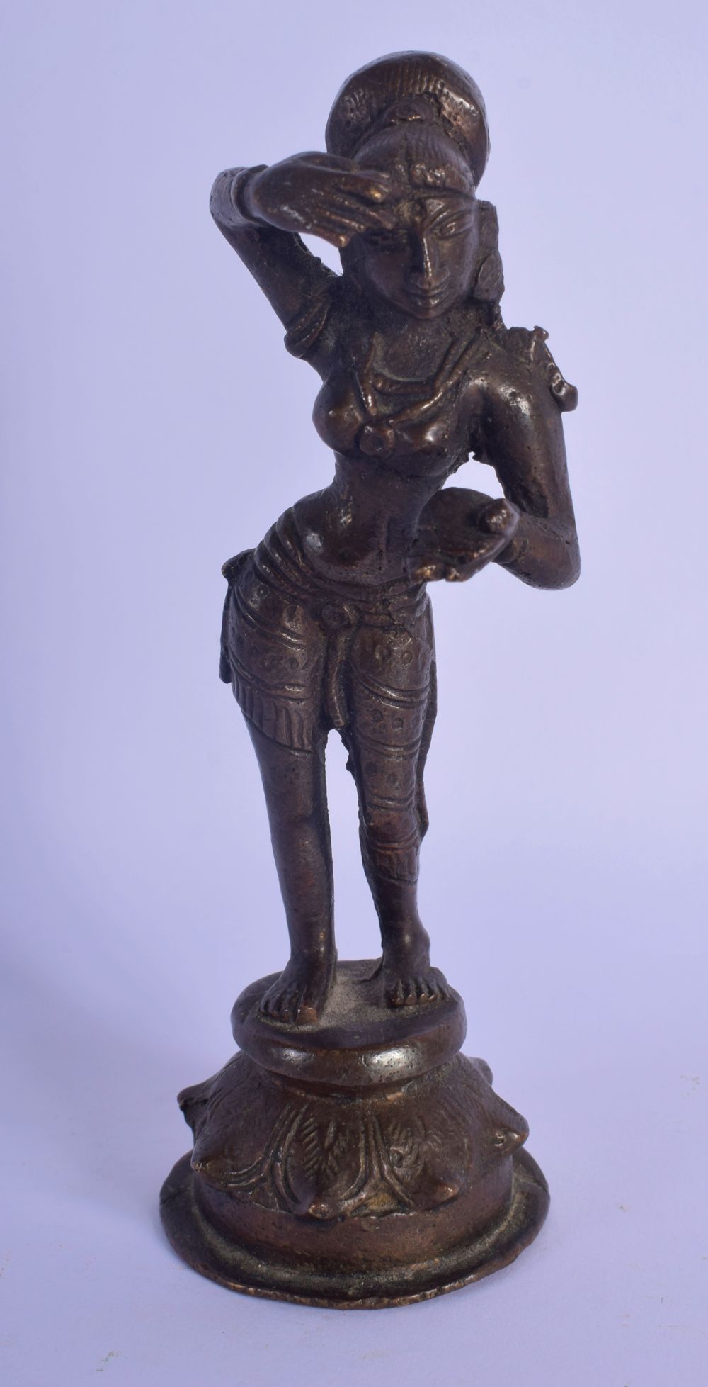 A 19TH CENTURY INDIAN BRONZE FIGURE OF A STANDING BUDDHIST DEITY modelled applying a motif to her fo