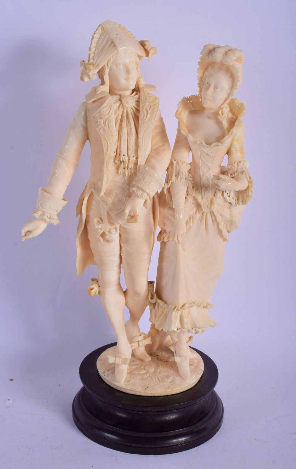 A 19TH CENTURY EUROPEAN CARVED IVORY FIGURAL GROUP modelled as a dandy and female upon a wooden base