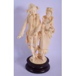 A 19TH CENTURY EUROPEAN CARVED IVORY FIGURAL GROUP modelled as a dandy and female upon a wooden base