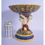 A 19TH MINTON MAJOLICA PEDESTAL DOUPLE PUTTI CENTREPIECE modelled upon a base overlaid with flowers.
