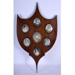 A SET OF SEVEN 19TH CENTURY EUROPEAN PAINTED IVORY PORTRAIT MINIATURES within a wooden shield. 56 cm