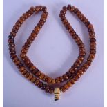 AN UNUSUAL EARLY 20TH CENTURY TRIBAL CARVED IVORY AND AMBER NECKLACE of regimented form. 280 grams.