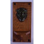 A CHARMING ARTS AND CRAFTS BRONZE MOUNTED OAK WALL PLINTH formed with a theatrical mask head. 40 cm