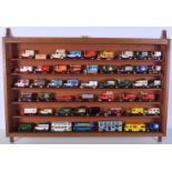 A collection of Matchbox and Lledo coaches and trade model vehicles in a wooden display cabinet. (Qt