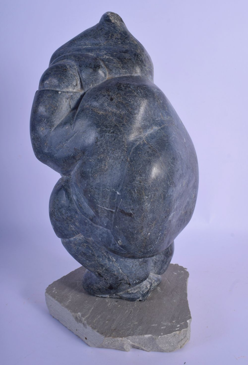 A LARGE NATIVE AMERICAN CANADIAN INUIT CARVED STONE FIGURE modelled holding a fish upon a stone base - Image 2 of 4