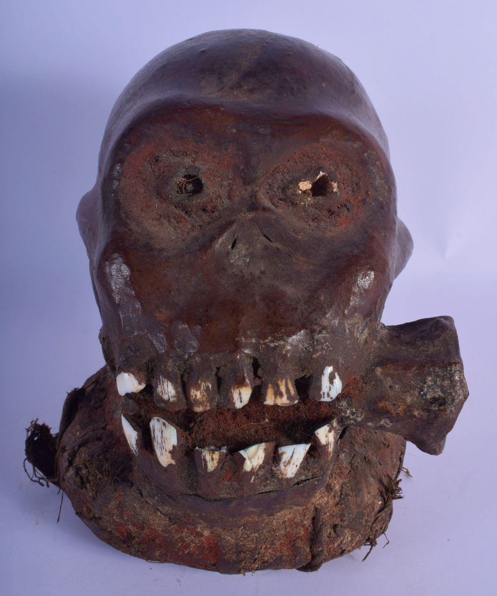 A RARE EARLY 20TH CENTURY AFRICAN TRIBAL ANIMAL SKIN MONKEY SKULL modelled with a bone within its mo