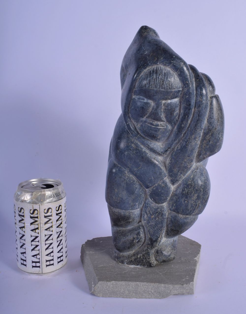 A LARGE NATIVE AMERICAN CANADIAN INUIT CARVED STONE FIGURE modelled holding a fish upon a stone base