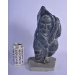 A LARGE NATIVE AMERICAN CANADIAN INUIT CARVED STONE FIGURE modelled holding a fish upon a stone base