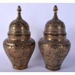 A PAIR OF 19TH CENTURY PERSIAN QAJAR BRASS VASES AND COVERS decorated with Buddhistic figures. 28 cm