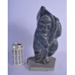 A LARGE NATIVE AMERICAN CANADIAN INUIT CARVED STONE FIGURE modelled holding a fish upon a stone base