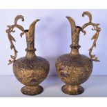 A large pair of South East Asian repoussé gilded metal ewers heavily decorated with figures, elepha