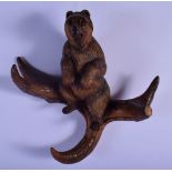 A 19TH CENTURY BAVARIAN BLACK FOREST HANGING HAT COAT RACK modelled as a seated bear. 27 cm x 24 cm.