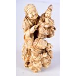 A 19TH CENTURY JAPANESE MEIJI PERIOD CARVED IVORY OKIMONO modelled as a male with two other figures.
