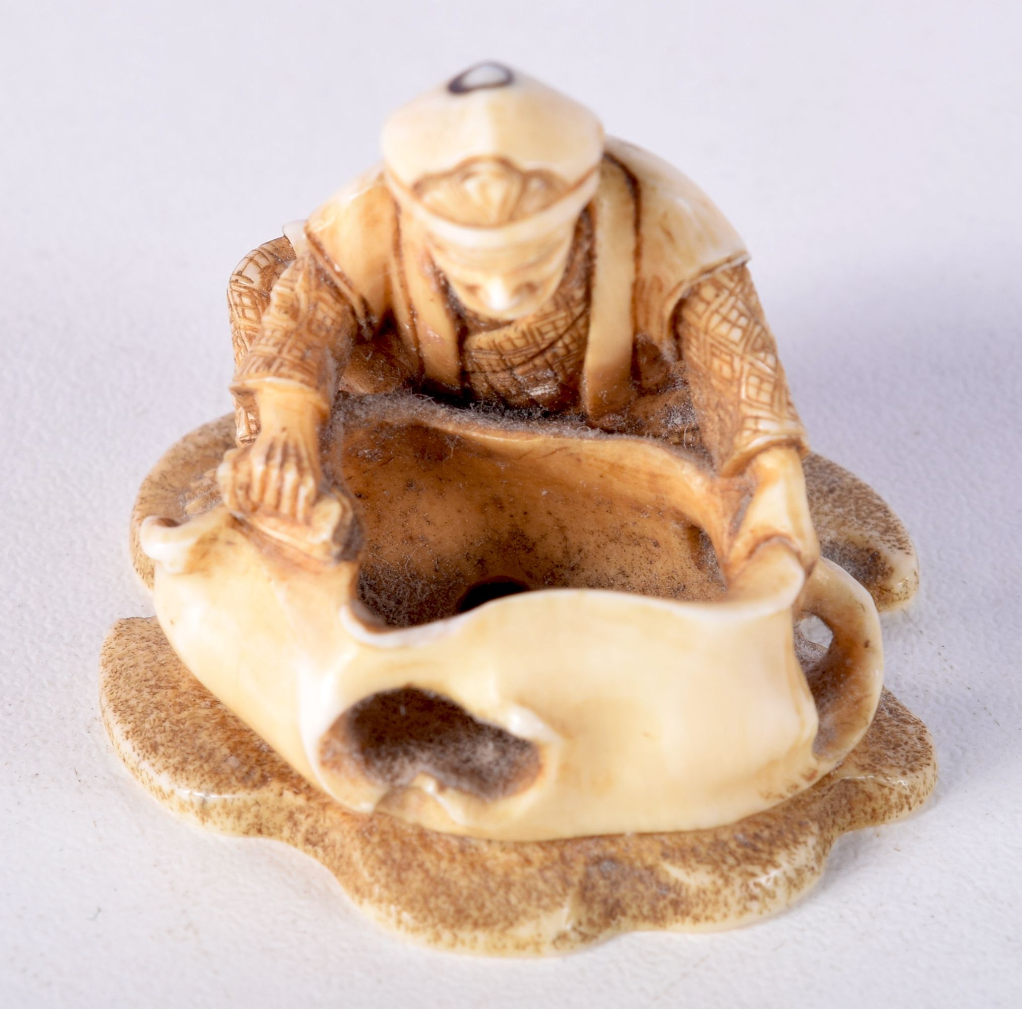 A 19TH CENTURY JAPANESE MEIJI PERIOD CARVED IVORY NETSUKE modelled as a male holding a sack. 3 cm x