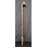 An early wooden walking cane carved with a mans head and a dog handle 84cm.