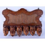 A RARE EARLY 20TH CENTURY EUROPEAN CARVED WOOD WALL MOUNTED PIPE RACK formed as mischievous mask hea