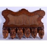 A RARE EARLY 20TH CENTURY EUROPEAN CARVED WOOD WALL MOUNTED PIPE RACK formed as mischievous mask hea