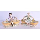 A PAIR OF 19TH CENTURY EUROPEAN TWIN HANDLED PORCELAIN TABLE SALTS modelled as figures upon baskets.