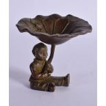 A BRONZE OF A SEATED BOY HOLDING ALOFT A LILY PAD. 6.4cm x 6.2cm