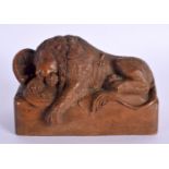 A 19TH CENTURY CARVED TREEN FIGURE OF A RECLINING LION modelled beside a shield. 10 cm x 8 cm.