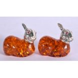 A PAIR OF RABBIT FIGURES WITH AMBER TYPE BODIES AND WHITE METAL HEADS WITH GEM SET EYES. 4cm x 4.7c